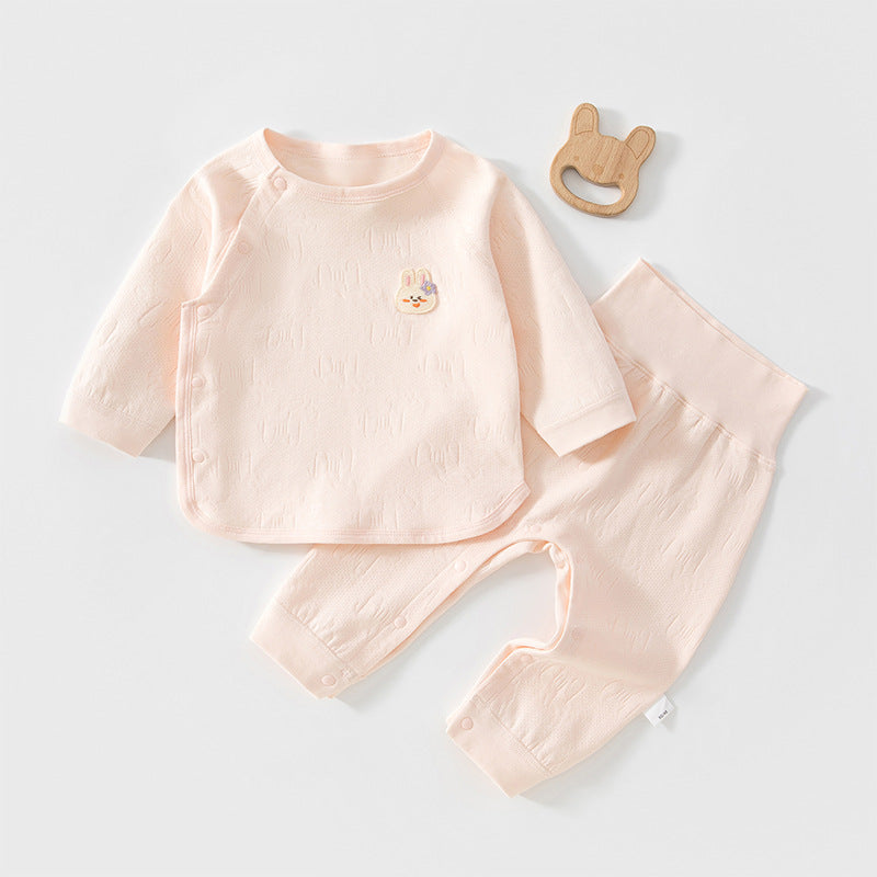 Rosa Baby-Set mit Wickeljacke und hoher Hose neben einem Holzspielzeug
