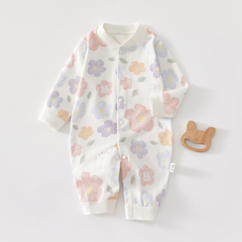 Baby-Strampler mit Blumenmuster und Druckknöpfen neben einem Holzspielzeug
