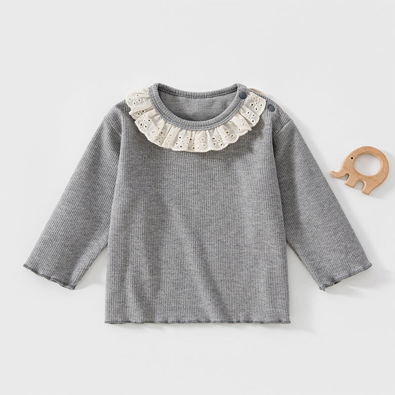 Graues Baby-Langarmshirt mit Spitzenkragen neben einem Holzspielzeug