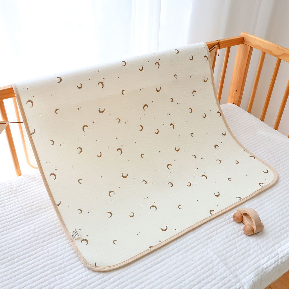 Baumwoll-Unterlage mit Mondmuster, über ein Babybett gelegt