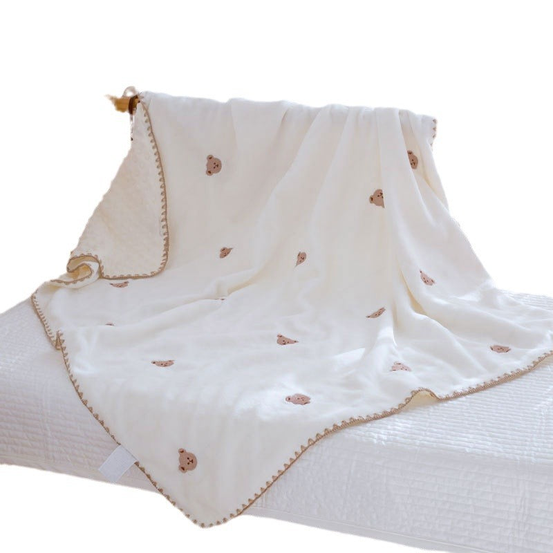 Weiße Fleece-Decke mit gestickten Bärchen und Zierrand über einem Bett