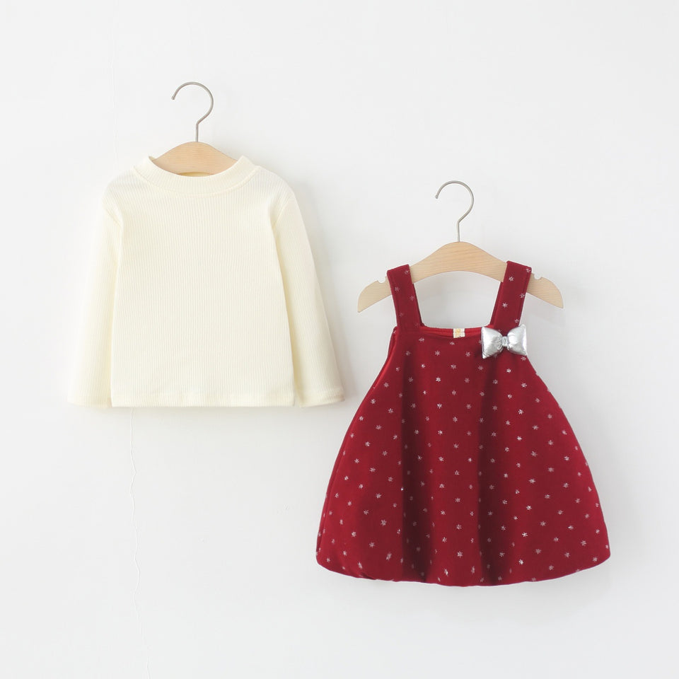 Cremefarbenes Langarmshirt und rotes Trägerkleid nebeneinander am Kleiderbügel