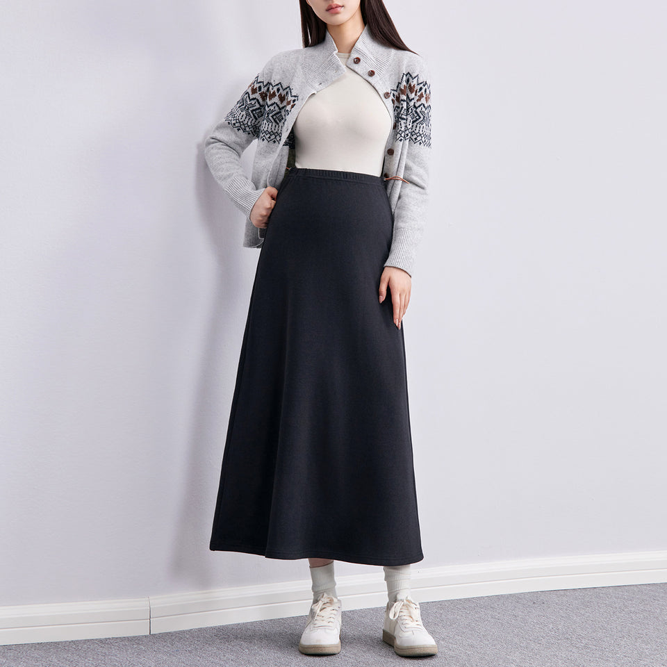 Frau in schwarzem langen Umstandsrock mit Strickjacke