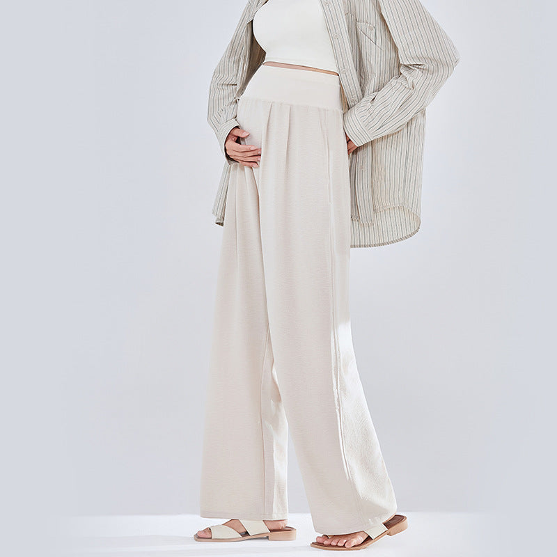 Frau in beiger weiter Umstandshose mit Strickjacke