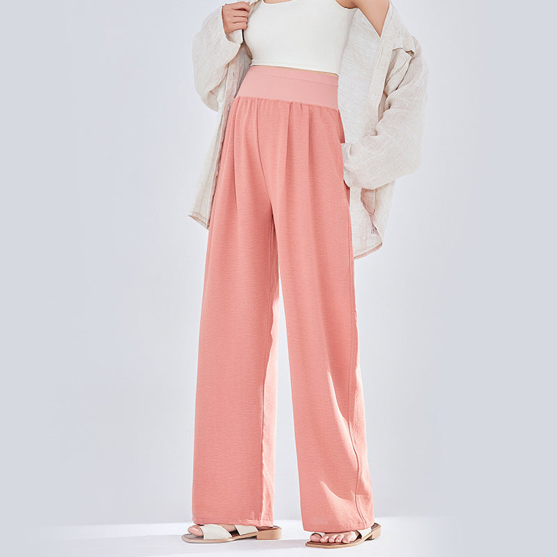 Frau in rosa weiter Umstandshose mit Strickjacke