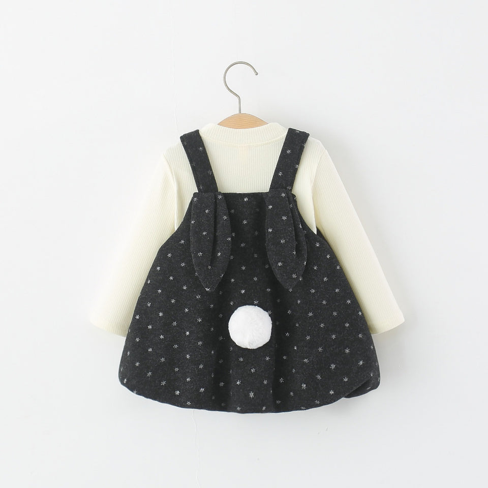 Schwarzes Trägerkleid mit Hasenohren und Bommelschwanz über cremefarbenem Langarmshirt