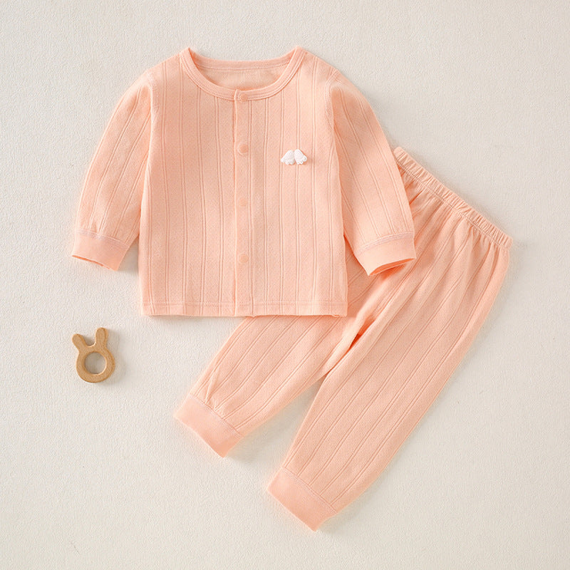 Rosa Baby-Set mit Wolken-Applikation neben einem Holzspielzeug