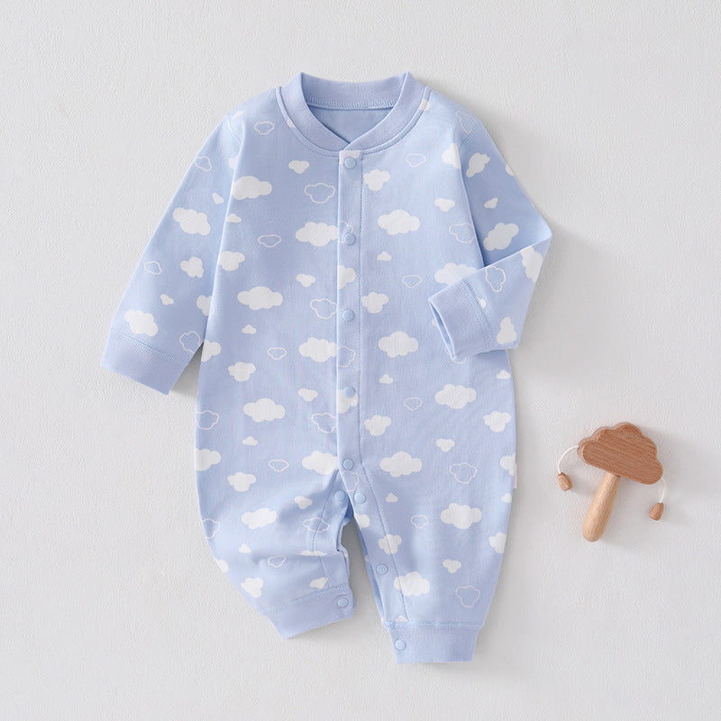 Hellblauer Baby-Strampler mit weißen Wolken neben einem Holzspielzeug