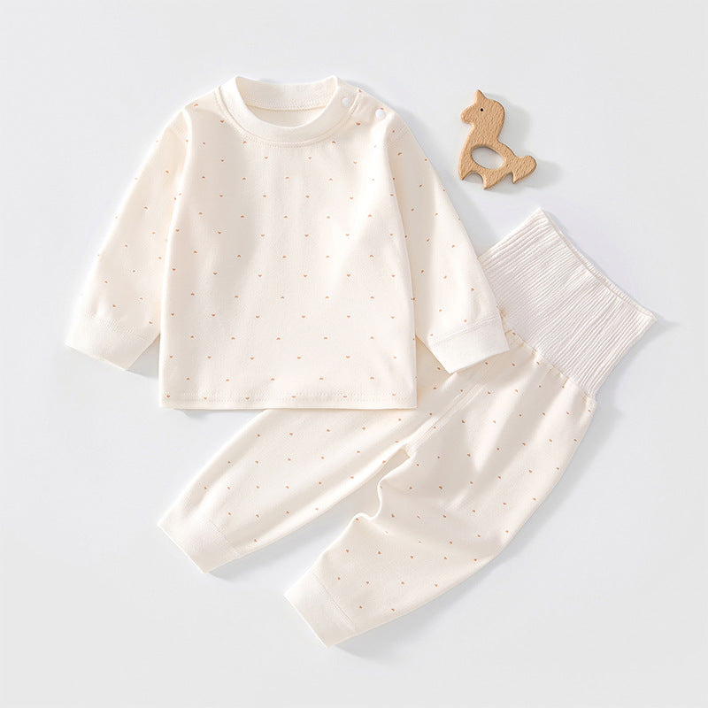 Cremefarbenes Baby-Set mit Herzchen neben einem Holzspielzeug
