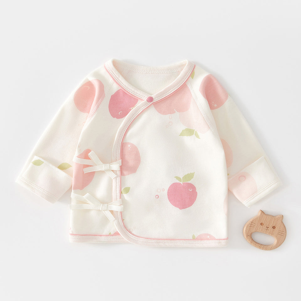 Wickelshirt mit Pfirsich-Muster neben einem Holzspielzeug