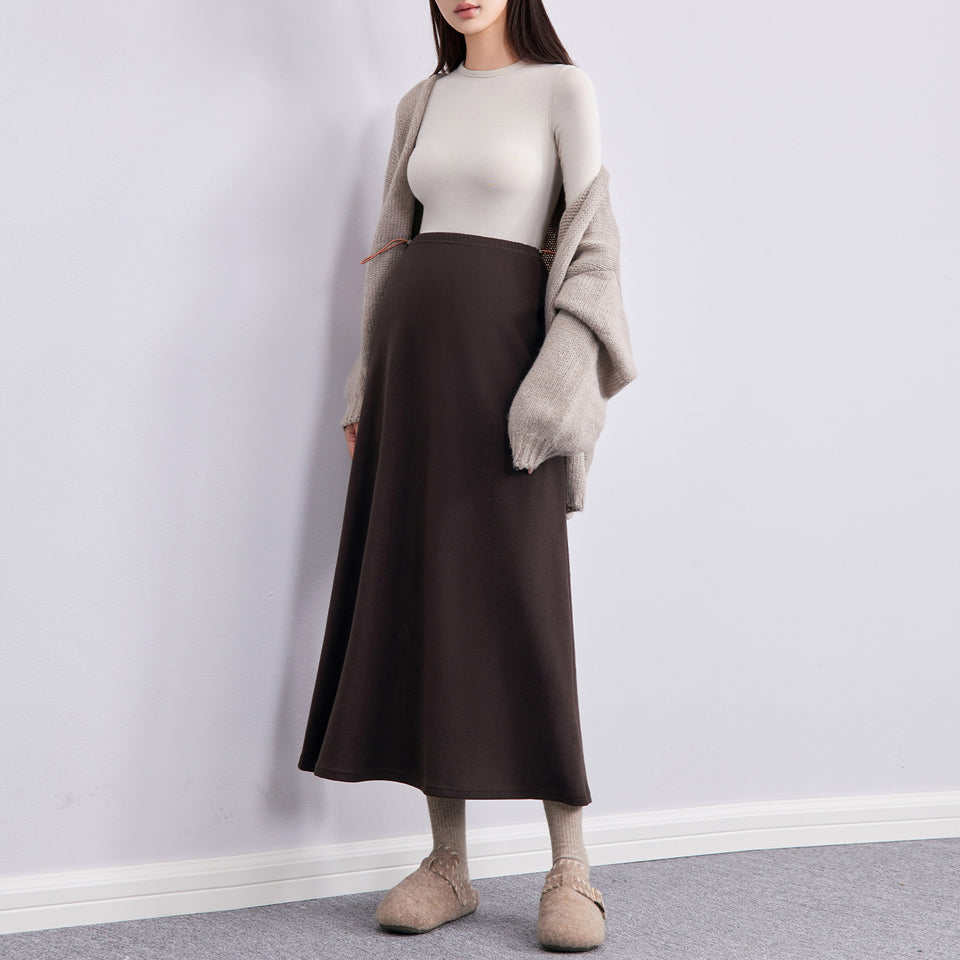 Frau in braunem langen Umstandsrock mit Strickjacke