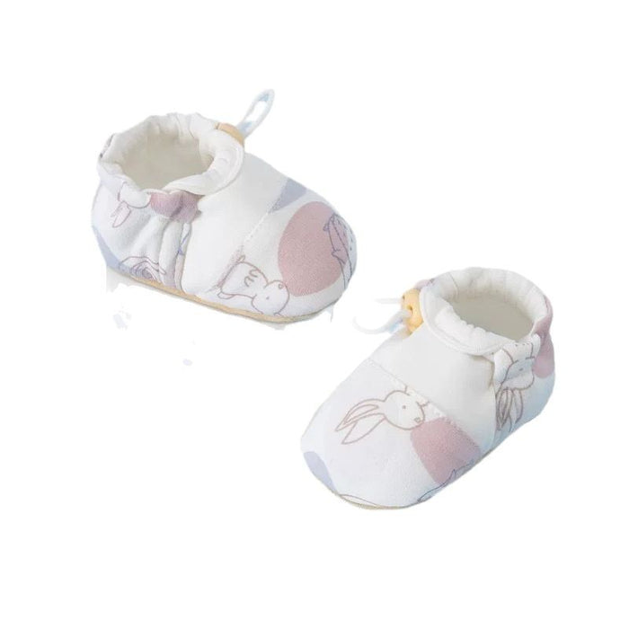 Zwei Babyschuhe in Weiß mit Hasen und rosa Flächen, freigestellt auf weißem Hintergrund