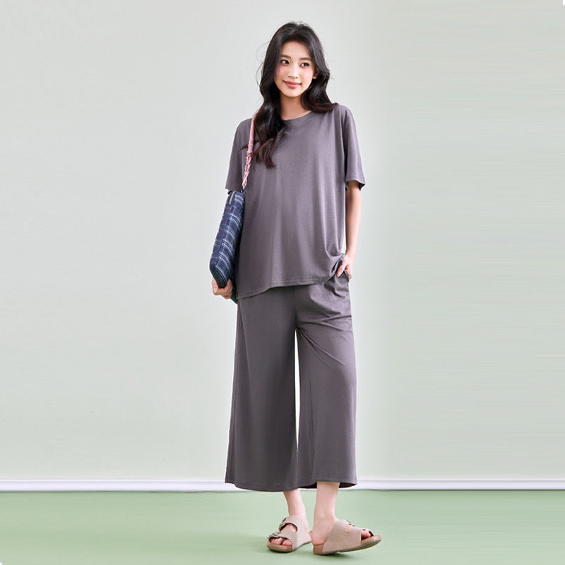 Frau in grauem Shirt und weiter grauer Hose mit Tasche