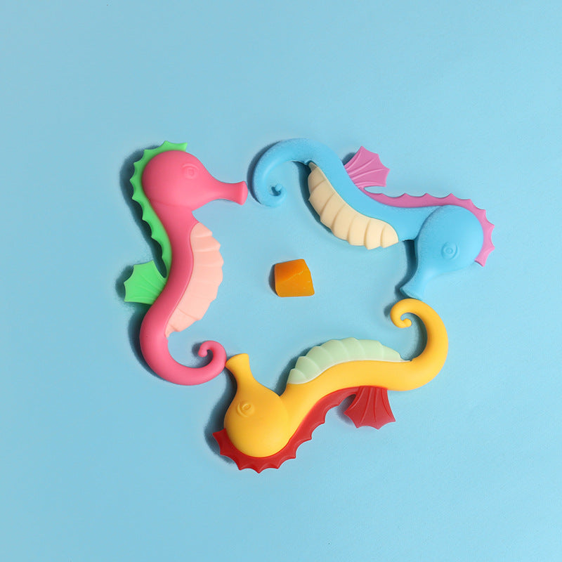 Drei Seepferdchen-Beißringe aus Silikon in Gelb, Hellblau und Rosa auf blauem Grund