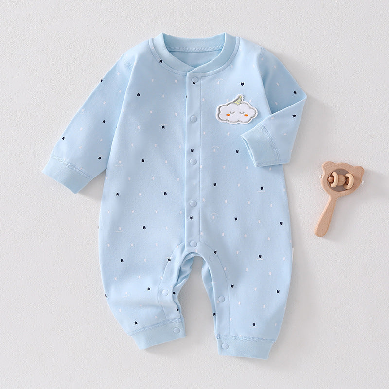 Hellblauer Baby-Strampler mit Pünktchen neben einem Holzspielzeug