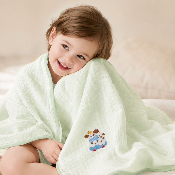 Kind in mintfarbenes Musselin-Badetuch mit Stickerei eingewickelt