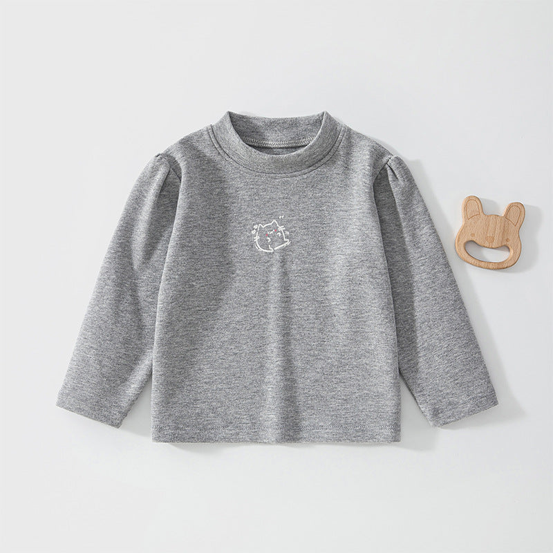 Graues Baby-Langarmshirt mit Puffärmeln neben einem Holzspielzeug
