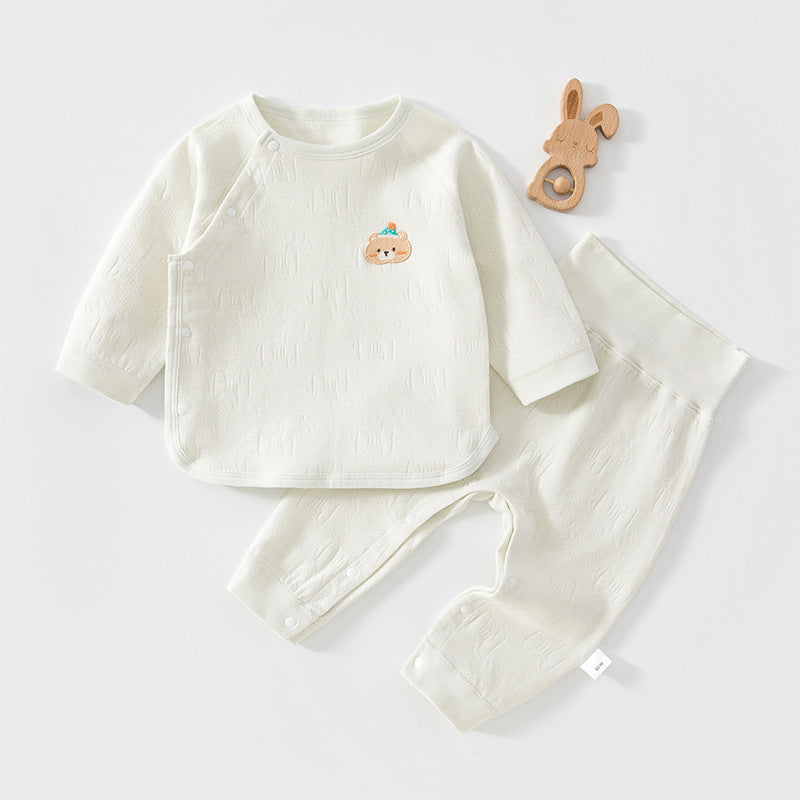 Mintfarbenes Baby-Set mit kleiner Tier-Applikation neben einem Holzspielzeug