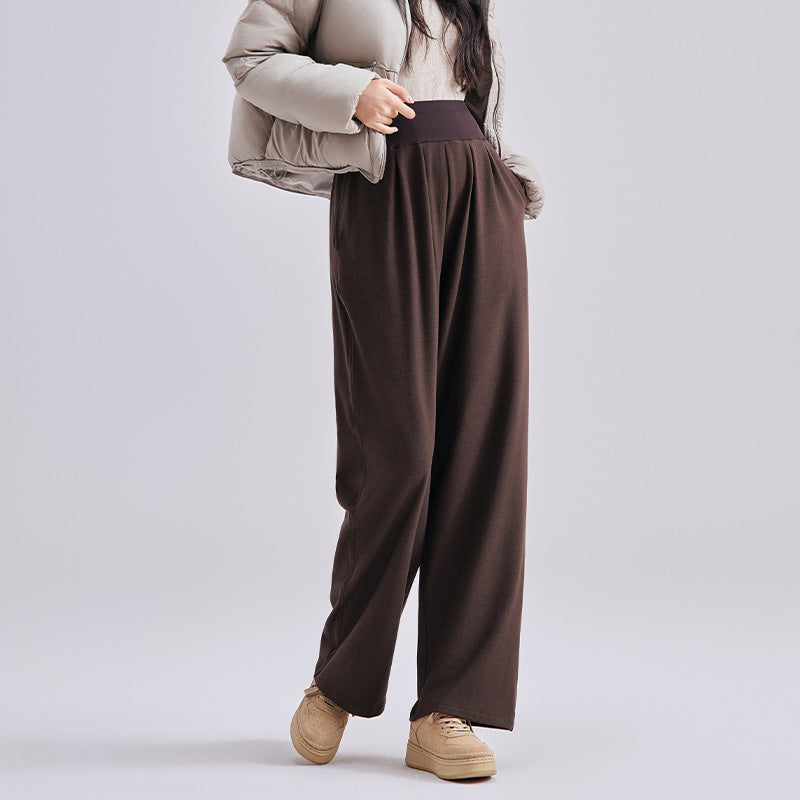 Frau in brauner weiter Umstandshose mit geradem Bein, dazu Daunenjacke