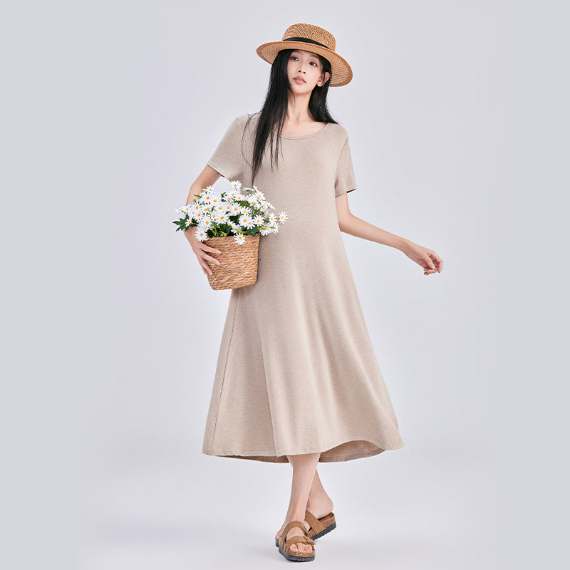 Frau in beigem langem Strickkleid mit Strohhut