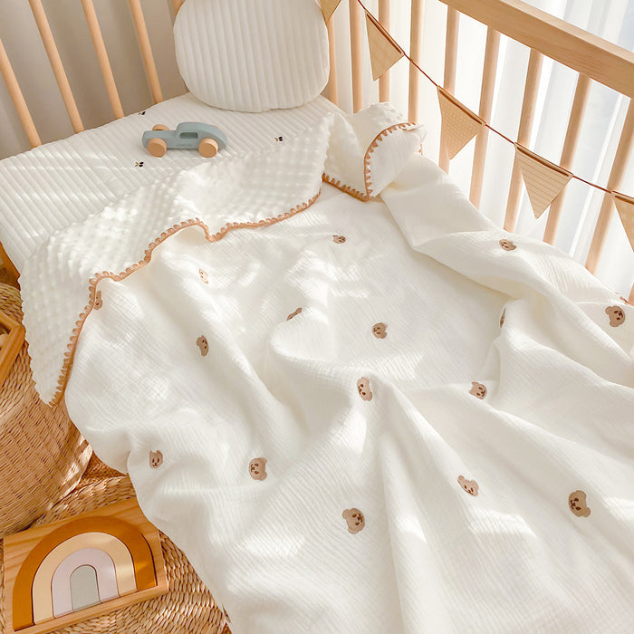 Weiße Babydecke mit gesticktem Bären im Babybett