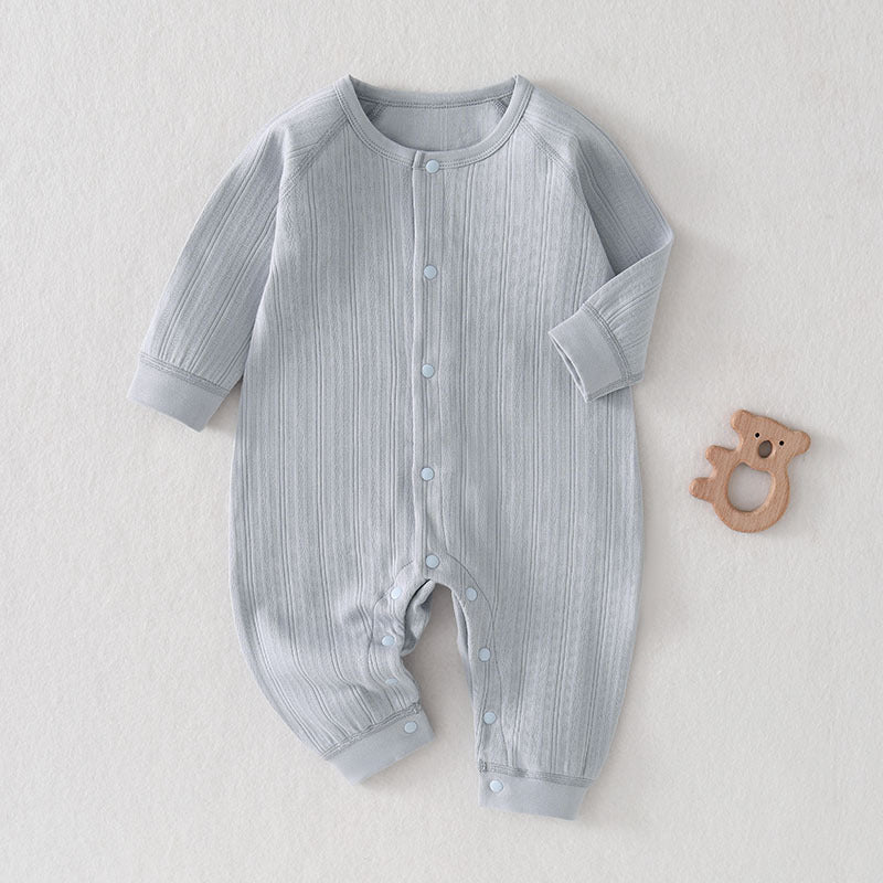 Hellblauer Baby-Strampler aus gerippter Baumwolle neben einem Holzspielzeug