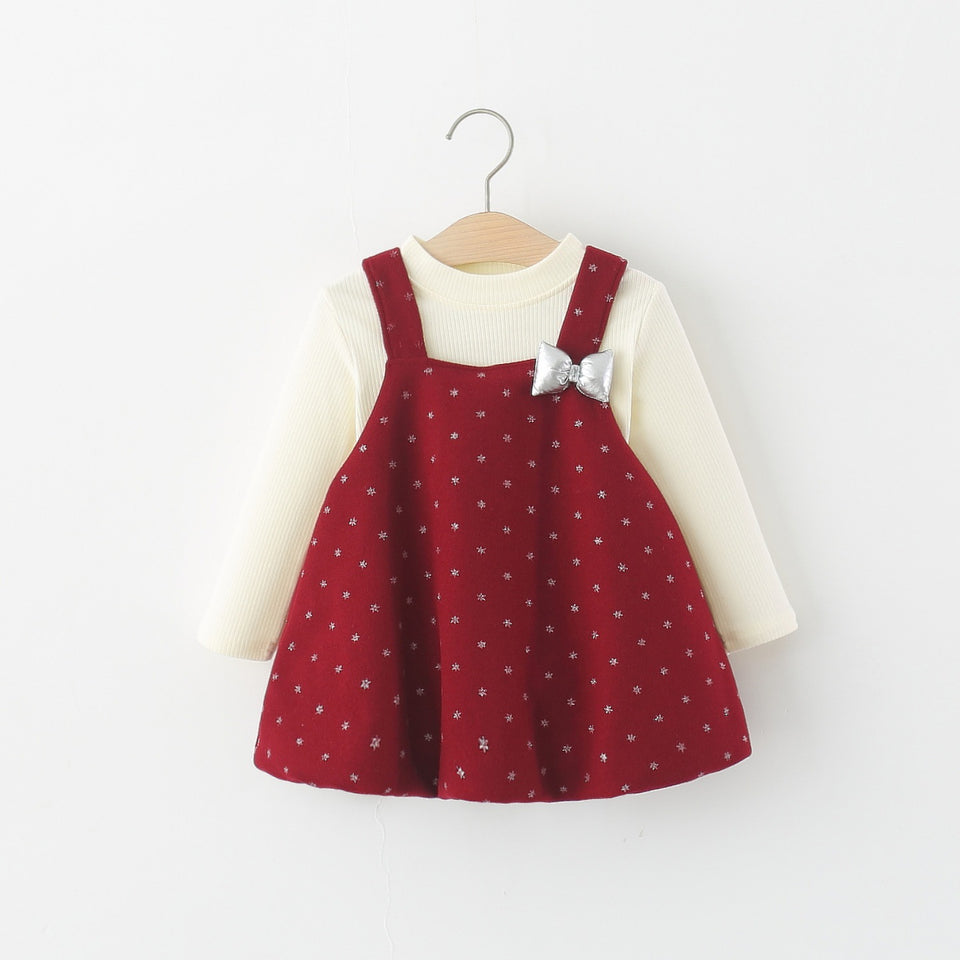 Rotes Trägerkleid mit silberner Schleife über cremefarbenem Langarmshirt