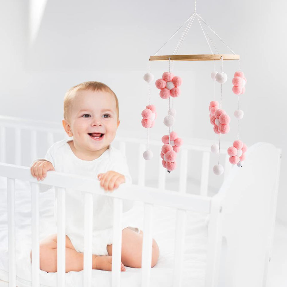 Mobile mit rosa Pompon-Blumen über einem weißen Babybett