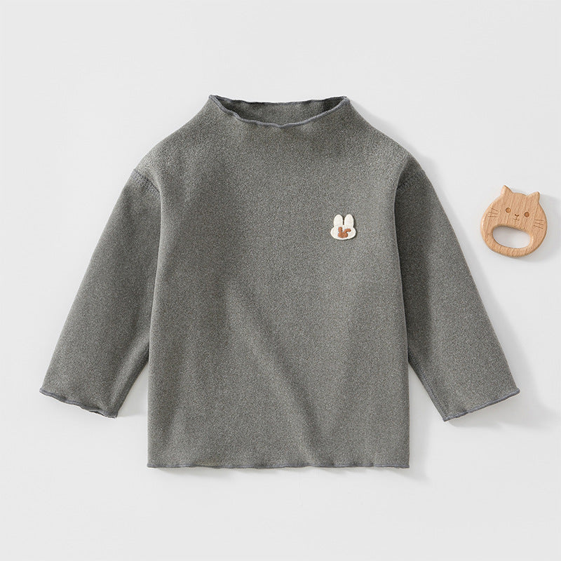 Graues Baby-Langarmshirt mit kleinem Hasen neben einem Holzspielzeug