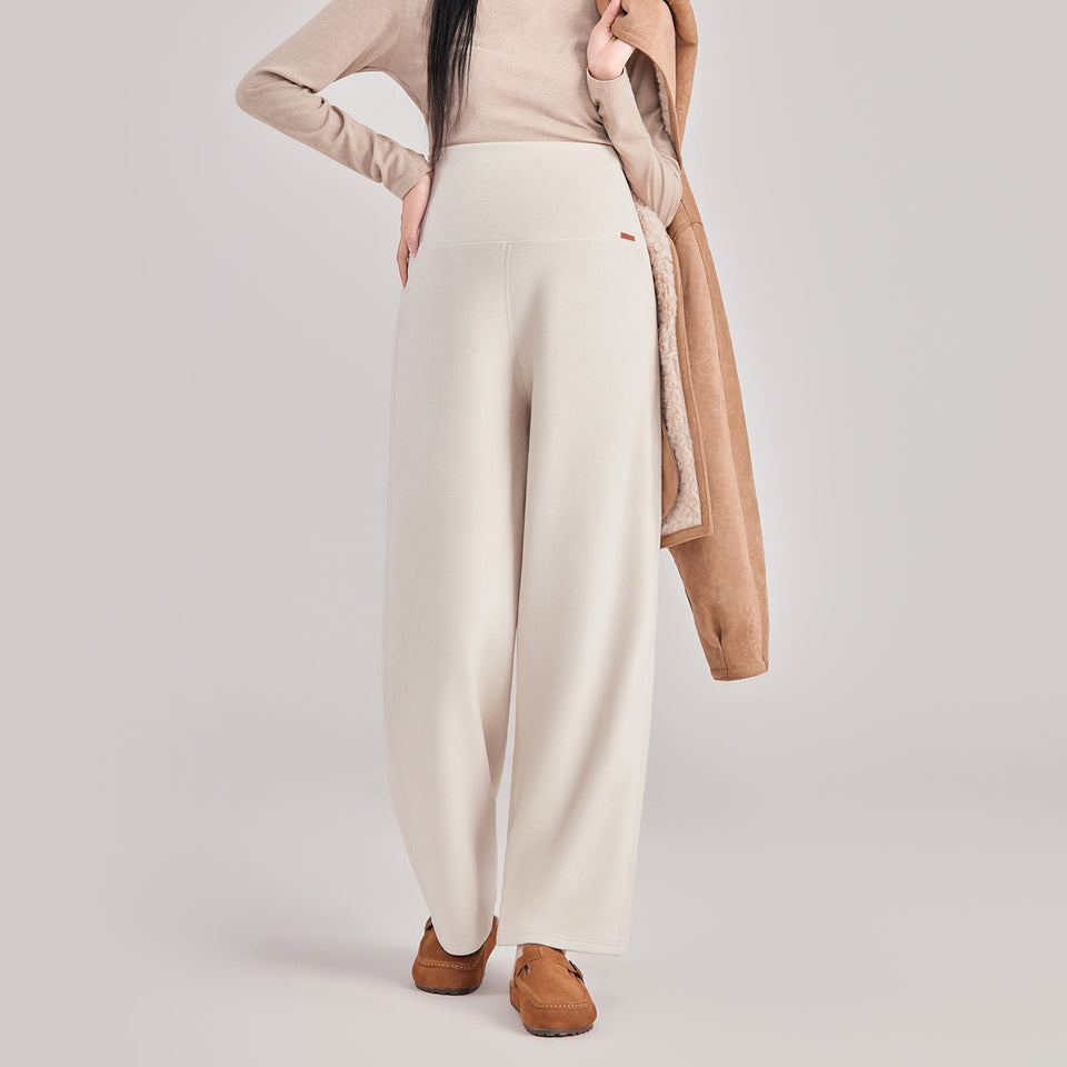 Frau in cremefarbener weiter Umstandshose mit Umschlagbund, dazu heller Pullover und Jacke