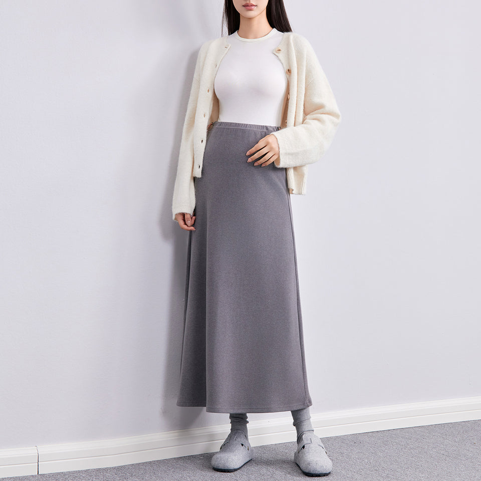 Frau in grauem langen Umstandsrock mit heller Strickjacke