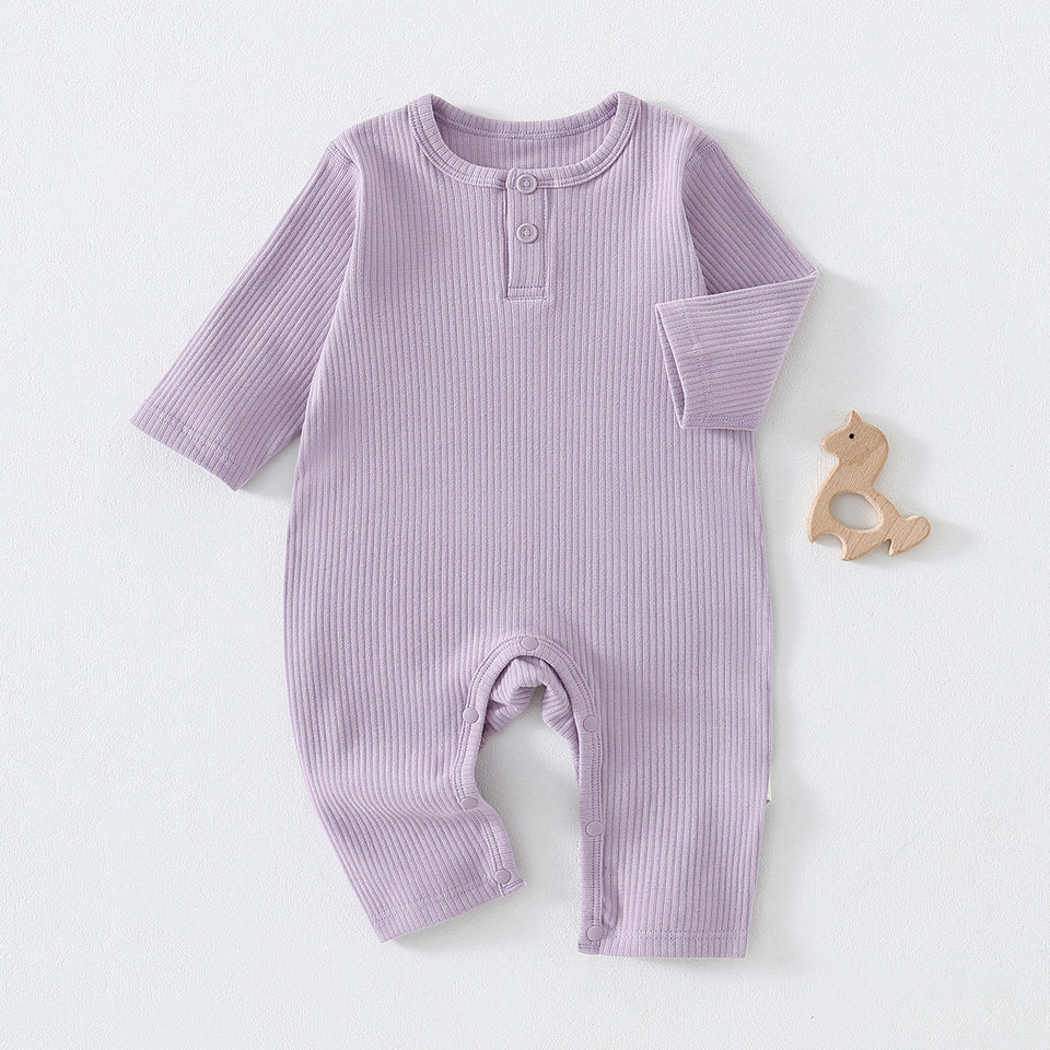 Fliederfarbener Baby-Strampler aus Rippstoff mit Holzspielzeug daneben