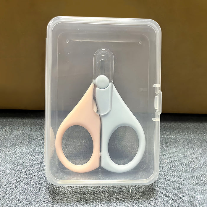 Baby-Nagelschere in Rosa und Hellblau mit Schutzkappe in einem durchsichtigen Etui auf dunklem Untergrund